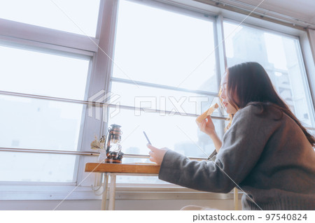 一位年輕女子在她的房間裡吃早餐的照片 一位年輕女子在她的房間裡吃早餐的照片 97540824