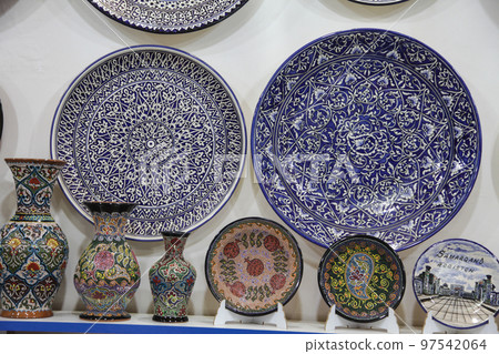 Ceramic souvenir plates, vases, tea sets on the shelves of a store in Samarkand in Uzbekistan. 29.04.2019 Ceramic souvenir plates, vases, tea sets on the shelves of a store in Samarkand in Uzbekistan. 29.04.2019 97542064