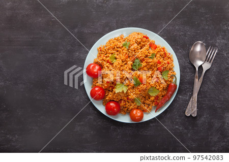 Jollof rice with parsley on a plate on a black background. National cuisine of Africa. Jollof rice with parsley on a plate on a black background. National cuisine of Africa. 97542083