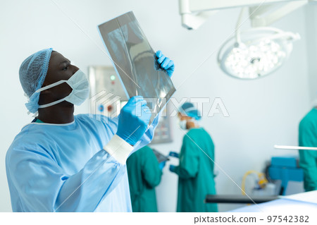 African american male surgeon studying x-ray in operating theatre, with copy space African american male surgeon studying x-ray in operating theatre, with copy space 97542382