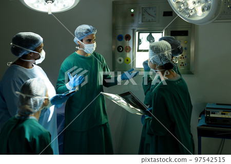 Diverse group of male and female surgeons in discussion, in operating theatre before operation Diverse group of male and female surgeons in discussion, in operating theatre before operation 97542515