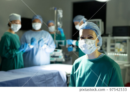 Portrait of smiling caucasian female surgeon in theatre for operation with colleagues, copy space Portrait of smiling caucasian female surgeon in theatre for operation with colleagues, copy space 97542533