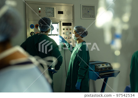Diverse male and female surgeon in discussion studying x-ray in operating theatre before operation Diverse male and female surgeon in discussion studying x-ray in operating theatre before operation 97542534