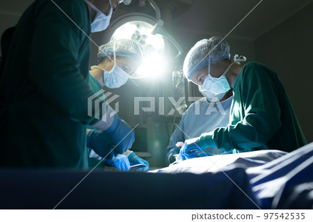 Diverse group of female and male surgeons operating on patient in operating theatre Diverse group of female and male surgeons operating on patient in operating theatre 97542535