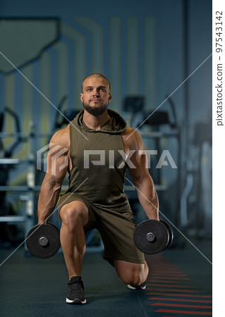Strong man doing lunges with dumbbells in the gym 97543142