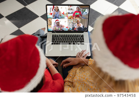 Diverse couple having christmas video call with diverse people 97543458
