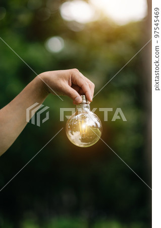 Hand holding light bulb on grass with solar energy and green background. power eco concept. 97545469