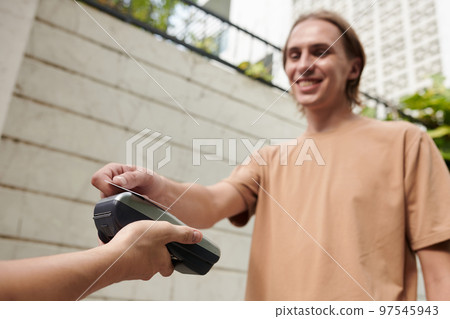 Smiling student paying for food delivery and swiping credit card 97545943