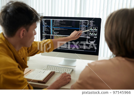 College students working on project together and discussing programming code and chart on screen 97545966