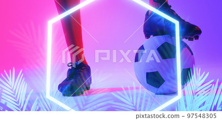 Low section of caucasian male player with leg on ball by illuminated plants and hexagon, copy space 97548305