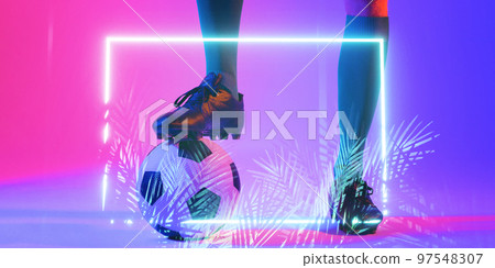 Low section of caucasian male player with leg on ball by illuminated plants and rectangle 97548307