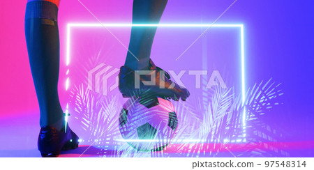 Low section of african american male player with leg on ball by illuminated rectangle and plants 97548314