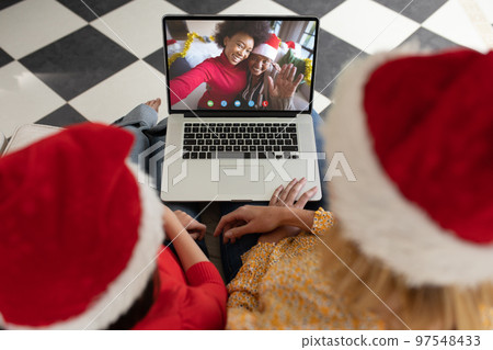 Caucasian mother and daughter having christmas video call with diverse people 97548433