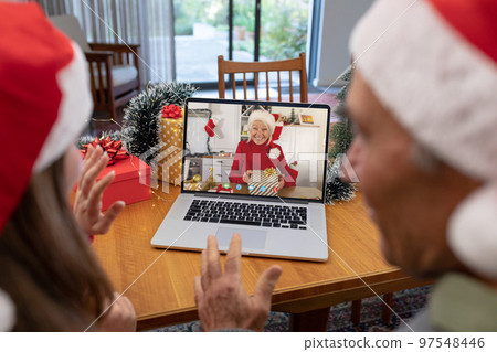 Caucasian father and daughter having christmas video call with senior caucasian woman Caucasian father and daughter having christmas video call with senior caucasian woman 97548446