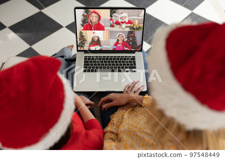 Caucasian mother and daughter in santa hats on christmas laptop video call with caucasian children 97548449