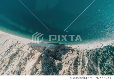 Aerial view from above on calm azure sea and volcanic rocky shores. Small waves on water surface in motion blur. Nature summer ocean sea beach background. Nobody. Holiday, vacation and travel concept 97548734