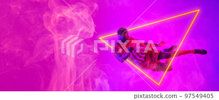 Full length of african american male soccer player jumping by illuminated triangle, copy space Full length of african american male soccer player jumping by illuminated triangle, copy space 97549405
