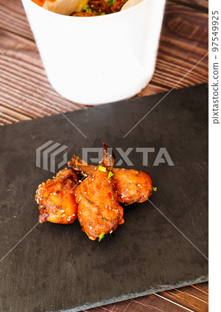 fried chicken with garlic and sesame in caramel on a black tray. fried chicken with garlic and sesame in caramel on a black tray. 97549925