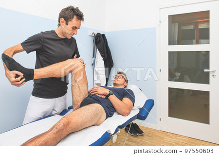 A physical therapist performs. a lower limb mobilization A physical therapist performs. a lower limb mobilization 97550603