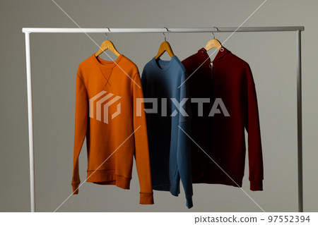Coloured sweatshirts displayed on clothing rail and copy space on white background Coloured sweatshirts displayed on clothing rail and copy space on white background 97552394