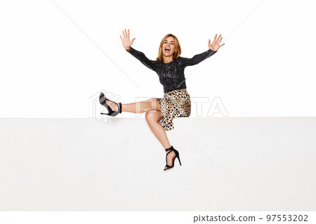 blonde woman with long legs sitting on white bench. 97553202