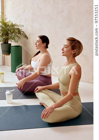 Calm Women Meditating Together. Girl And Instructor Sitting In Lotus Position 97553251