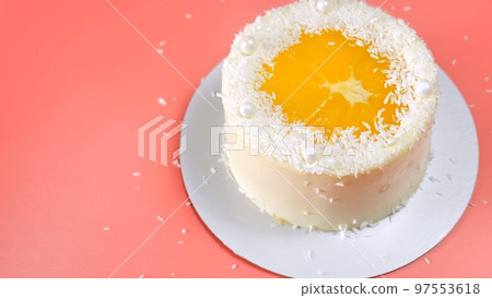Cake with orange and coconut shavings spun on a pink background. 97553618