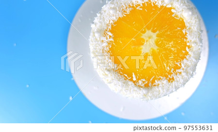 Cake with orange and coconut shavings spinning on a blue background. 97553631
