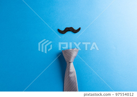 Composition of fake moustache and tie on blue background with copy space Composition of fake moustache and tie on blue background with copy space 97554012