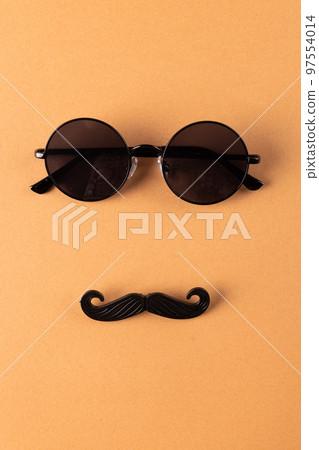 Composition of fake moustache and glasses on orange background with copy space 97554014