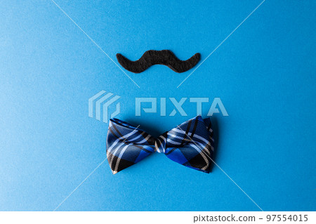 Composition of fake moustache and bow tie on blue background with copy space Composition of fake moustache and bow tie on blue background with copy space 97554015