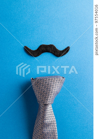 Composition of fake moustache and tie on blue background with copy space Composition of fake moustache and tie on blue background with copy space 97554016