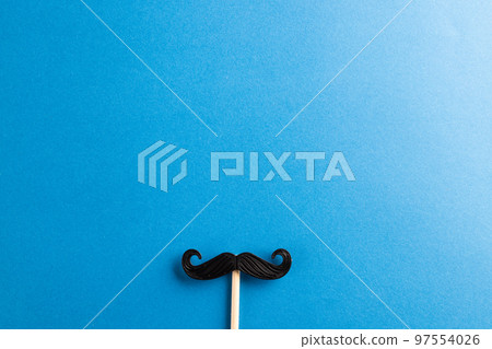 Composition of fake moustache on stick on blue background with copy space 97554026