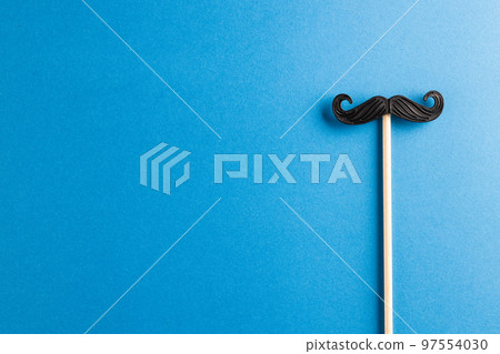 Composition of fake moustache on stick on blue background with copy space 97554030