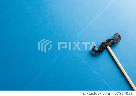 Composition of fake moustache on stick on blue background with copy space Composition of fake moustache on stick on blue background with copy space 97554031