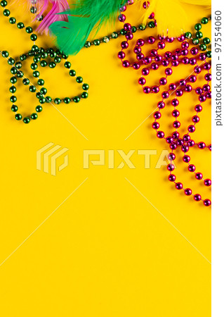 Composition of colourful mardi gras beads and feathers on yellow background with copy space 97554060