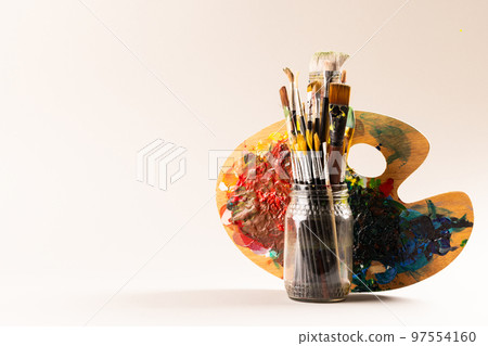 Composition of jar of painting brushes and palette on white background with copy space Composition of jar of painting brushes and palette on white background with copy space 97554160