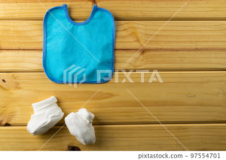 Close up of baby bib and shoes with copy space on wooden background 97554701