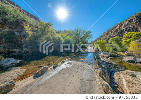 Water flowing over the bridge in the middle of rocky desert mountains at Sabino Canyon State Park 97555038