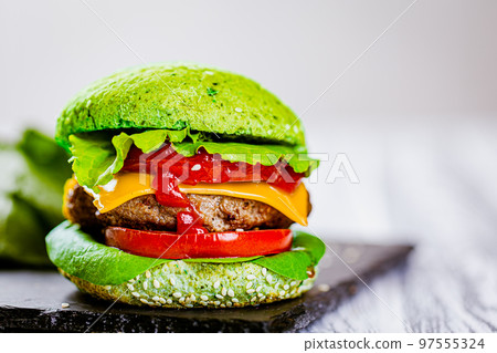 Closeup of green homemade burger with marble beef with veggies on wooden table. Selective focus Closeup of green homemade burger with marble beef with veggies on wooden table. Selective focus 97555324