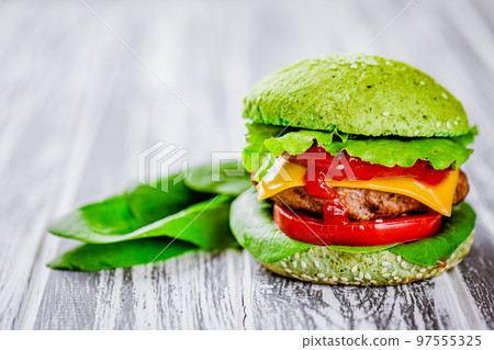 Front view of green homemade burger with marble beef with veggies, greenery on wooden table Front view of green homemade burger with marble beef with veggies, greenery on wooden table 97555325