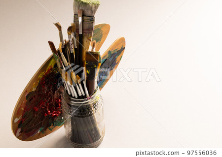 Composition of jar of painting brushes and palette on white background Composition of jar of painting brushes and palette on white background 97556036