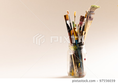 Composition of jar of painting brushes on white background 97556039