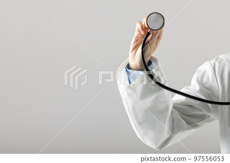 Midsection of caucasian doctor holding stethoscope on grey background with copy space Midsection of caucasian doctor holding stethoscope on grey background with copy space 97556053
