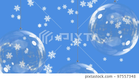 Snow falling over baubles on blue background 97557348
