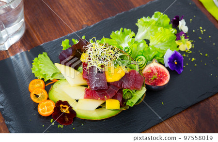 Close up of tasty salad of raw tuna, avocado, mango and greens 97558019