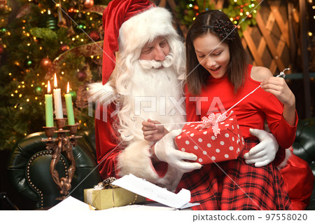 Santa Claus in a traditional costume with a girl in a room 97558020