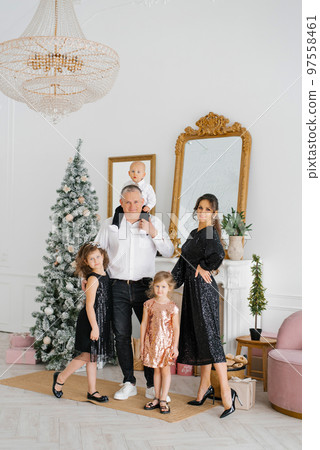 A stylish beautiful large family celebrates Christmas and New Year in the living room in their house near the Christmas tree A stylish beautiful large family celebrates Christmas and New Year in the living room in their house near the Christmas tree 97558461
