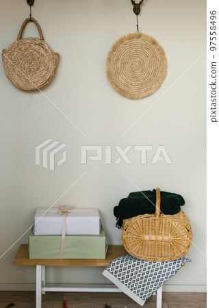 A minimalistic part of the house in a Scandinavian style. Wooden shop with gift boxes and wicker basket near beige wall 97558496