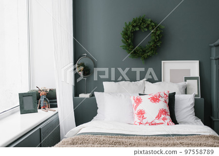 Stylish Christmas bedroom. Pillows on the bed and a wreath on the wall 97558789